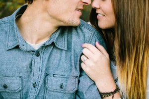 A couple snuggled up displaying her engagement ring