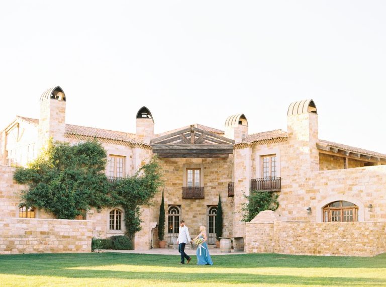 Christy and David holding hands and walking in front of Sunstone Villa during their engagement session