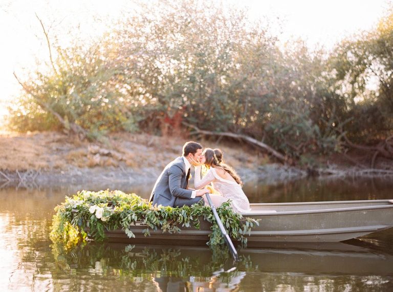 Bride and groom sitting in a boat on the pond kissing at Greengate Ranch and Vineyards