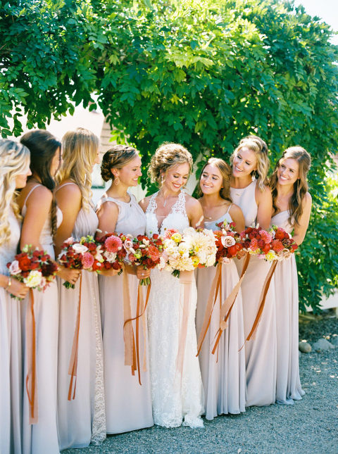 Whitney and her bridesmaids laughing and holding bouquets