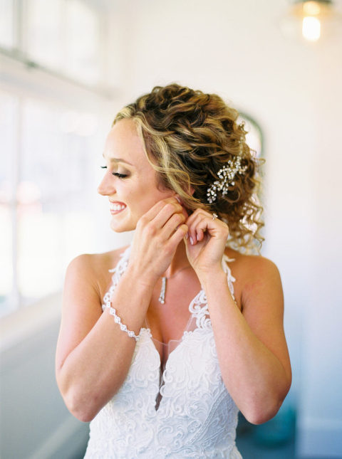 Whitney puts on her earrings in the bridal suite at Mattei's Tavern in Los Olivos