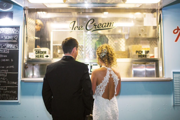 The bride and groom are waiting in line to get their ice cream from the McConnell's ice cream truck