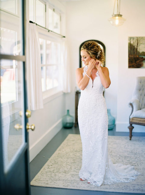 Bride putting on her earrings wearing a Willowby by Watters dress