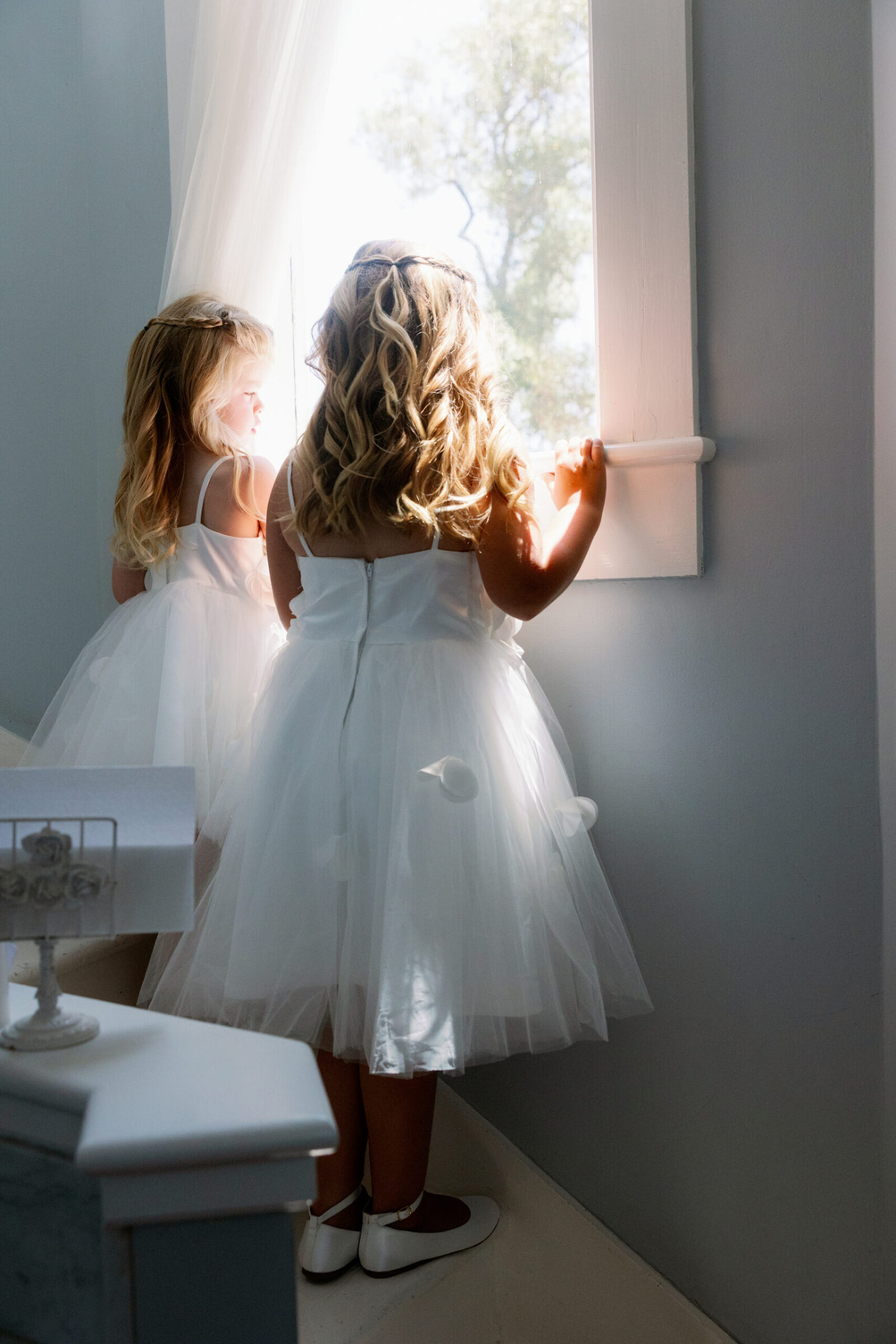 Two flower girls look excitedly through the window at the ceremony location below at Dana Powers House in Nipomo.